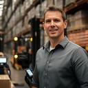 Logistikleiter in einer Lagerhalle mit Scanner und Palettenwagen